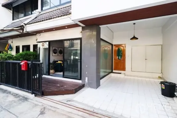 联排别墅 出租在Watthana, Bangkok - 联排别墅外观，落地推拉玻璃门、小露台与有顶车位，位于Thonglor一带。