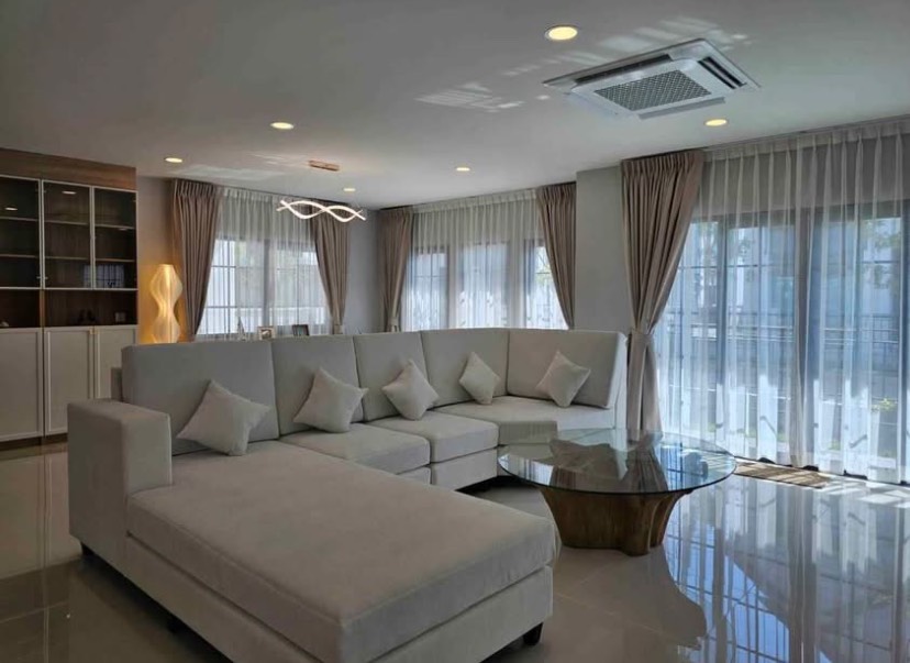 Detached House for rent in Bang Phli, Samut Prakan - Corner living area featuring an L‑shaped sofa, sculptural glass coffee table and full‑height curtains.