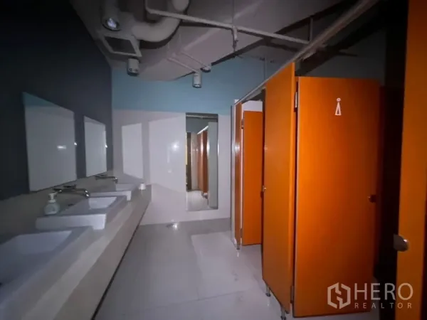 零售空间 出租在Khlong Toei, Bangkok - 配有多组洗手台、镜子和橙色隔间门的现代洗手间。