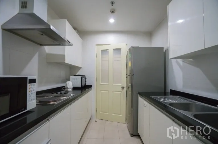 คอนโด ให้เช่าหรือขายในKhlong Toei, Bangkok - ครัวปิดสไตล์แกลเลอรี ตู้สีขาว เคาน์เตอร์สีดำ และเครื่องใช้ไฟฟ้า