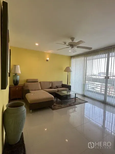 Condominium for sale in Watthana, Bangkok - Spacious living room with large windows, vertical blinds and balcony access.