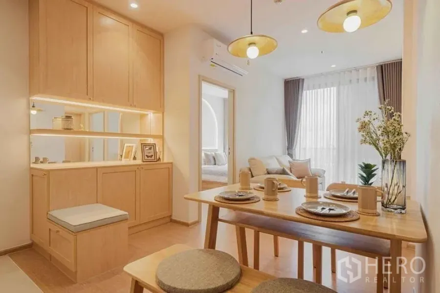 Condominium for rent in Watthana, Bangkok - Dining area with built-in cabinetry, pendant lights, and view toward the living room.