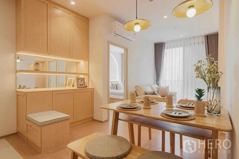 Condominium for rent in Watthana, Bangkok - Dining area with built-in cabinetry, pendant lights, and view toward the living room.