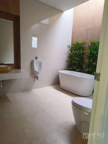 独立式住宅 出租在Phra Khanong, Bangkok - 明亮卫生间，独立浴缸、小便器、坐便器与绿植。