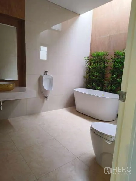 独立式住宅 出租在Phra Khanong, Bangkok - 明亮卫生间，独立浴缸、小便器、坐便器与绿植。