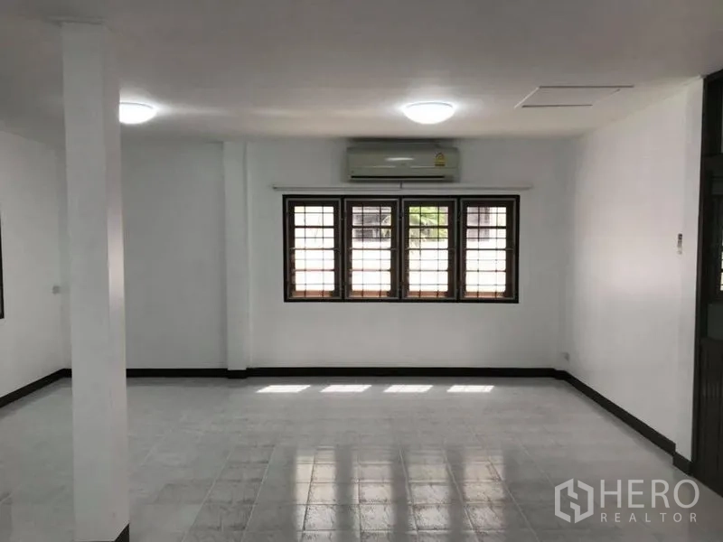 Detached House for rent in Khlong Toei, Bangkok - Spacious living area with white tile flooring, large window and air conditioner