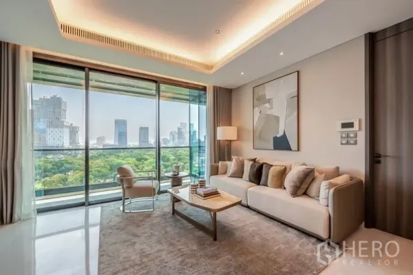 Condominium for rent or sale in Pathum Wan, Bangkok - Bright living room with floor-to-ceiling windows and park and skyline view in a Pathum Wan condo.