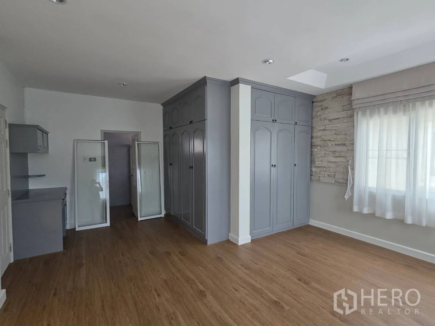 Detached House for sale in Lam Luk Ka, Pathum Thani - Bedroom with built-in gray wardrobes, study desk, and stone accent wall.
