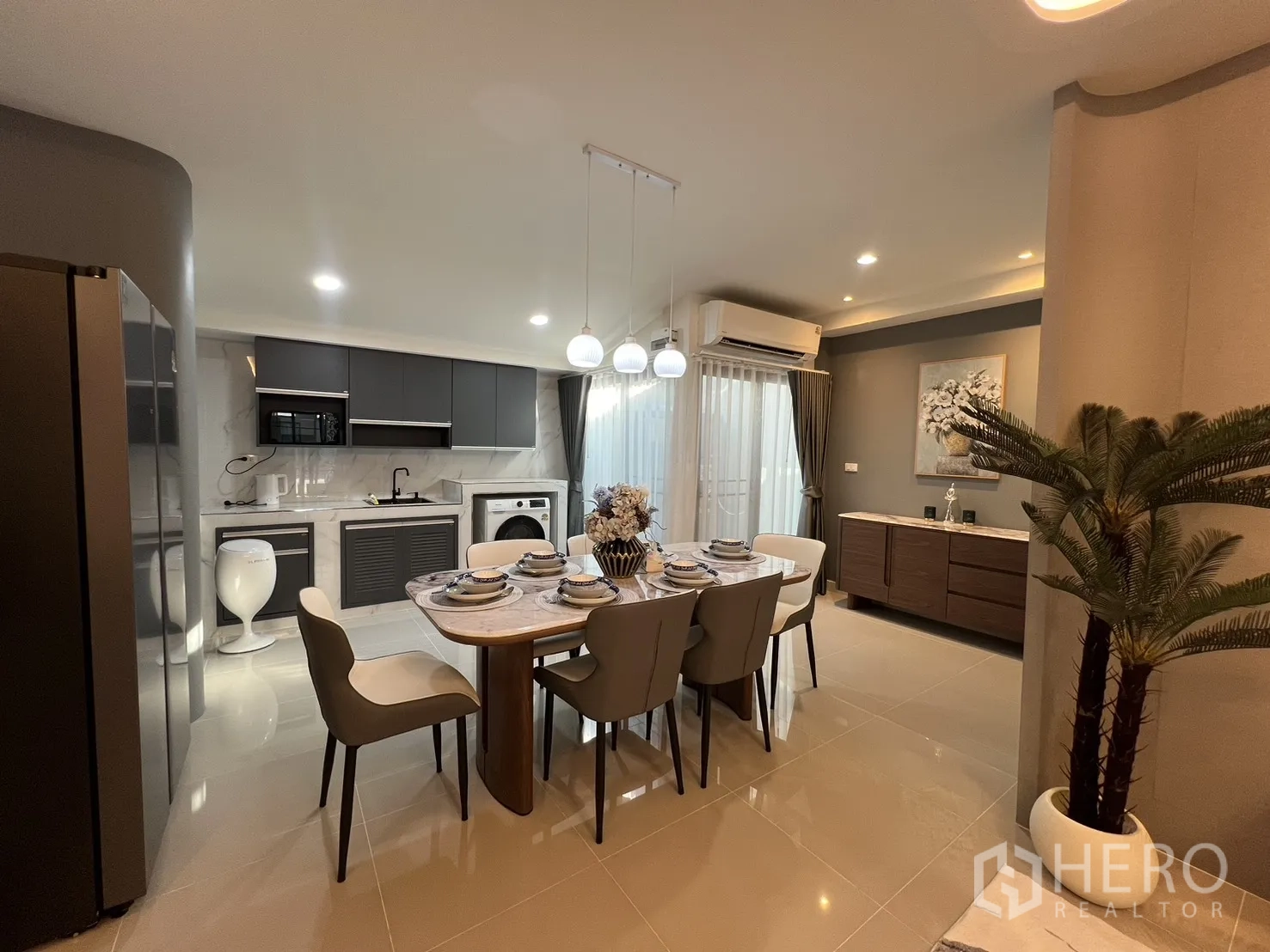 Townhouse for rent in Bang Phli, Samut Prakan - Open-plan kitchen and dining with grey cabinets, marble surfaces and pendant lights.