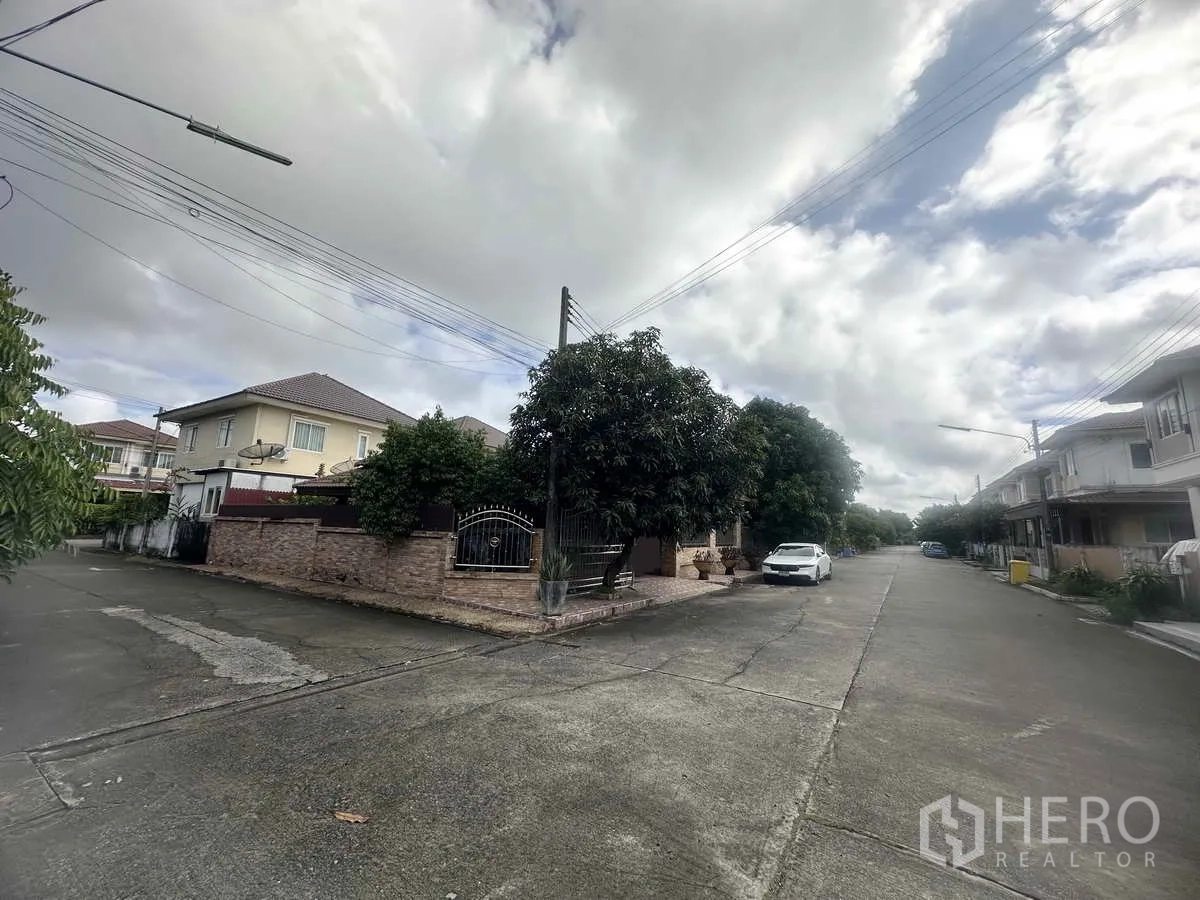 独立式住宅 出售在Pathum Thani - 小区内安静宽阔的街道，转角住宅与停车位。