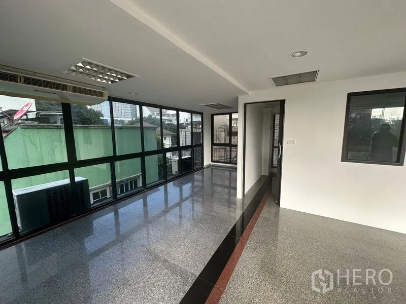 Office Space for rent in Sathon, Bangkok - Corner workspace with wraparound windows, glossy floors and a doorway to a private room.