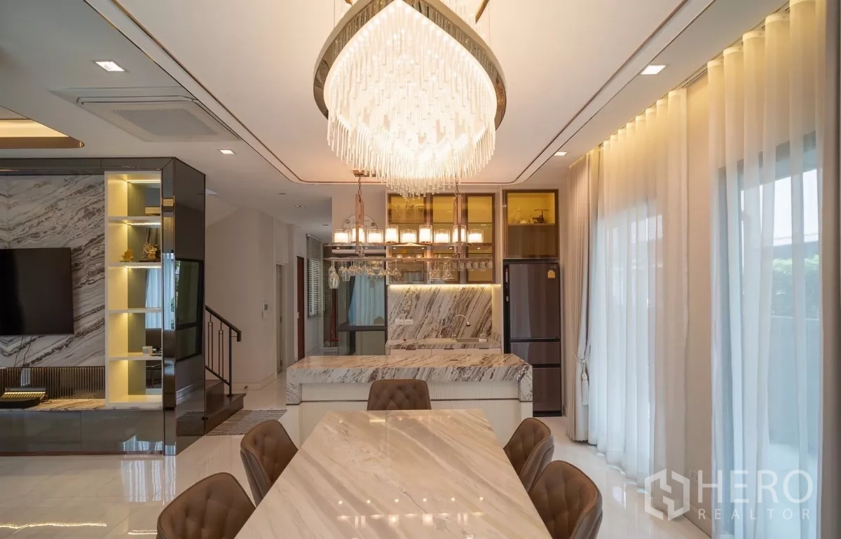 Detached House for rent or sale in Saphan Sung, Bangkok - Open‑plan dining and kitchen area with marble island and statement chandelier.