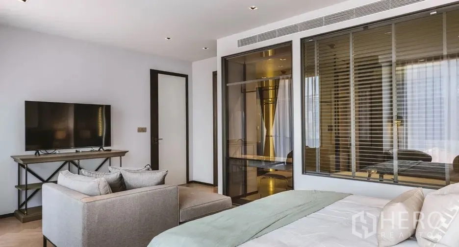 คอนโด ให้เช่าในWatthana, Bangkok - ห้องนอนมีชั้นวางทีวี ฉากกั้นกระจกไปยังห้องแต่งตัว และหน้าต่างบานใหญ่