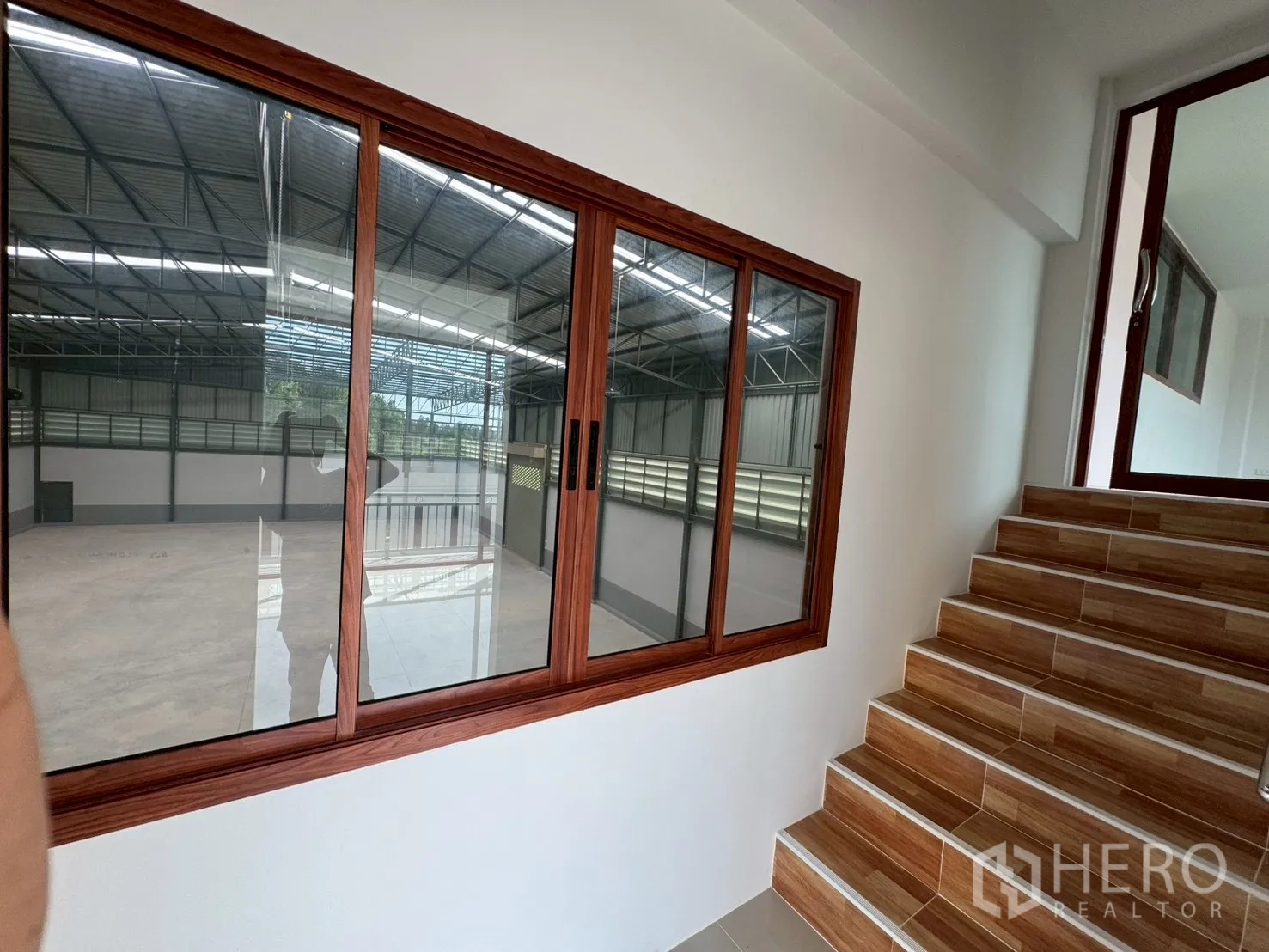 工厂 for sale in Mueang Samut Sakhon, Samut Sakhon - 走廊带推拉窗，可俯瞰仓库地面与楼梯。