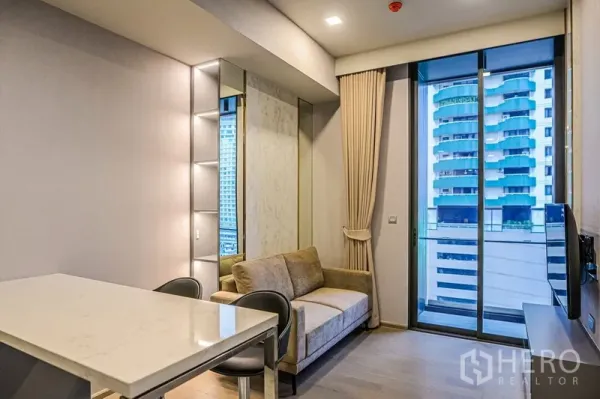 公寓 出租在Watthana, Bangkok - 客厅设米色沙发与落地窗，连接阳台，可观城市景观。