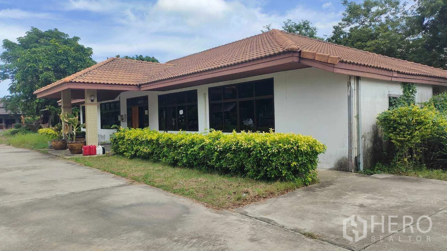 工厂 出售在Nikhom Phatthana, Rayong - 办公楼侧视图，修剪绿篱与铺装车道。