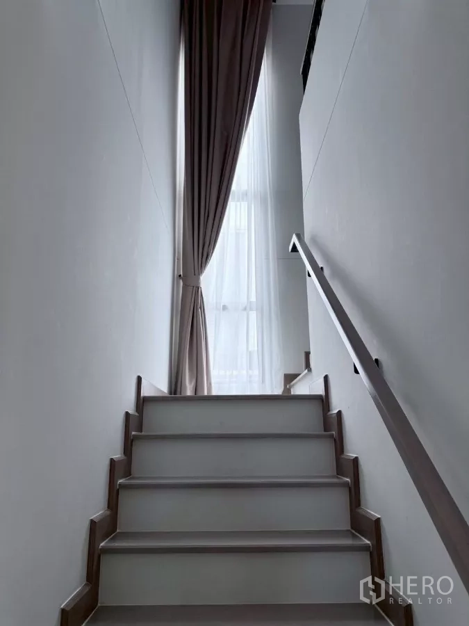 บ้าน ให้เช่าในLat Krabang, Bangkok - บันไดขึ้นชั้นบนพร้อมราวจับ รับแสงจากหน้าต่างสูงและผ้าม่านยาว