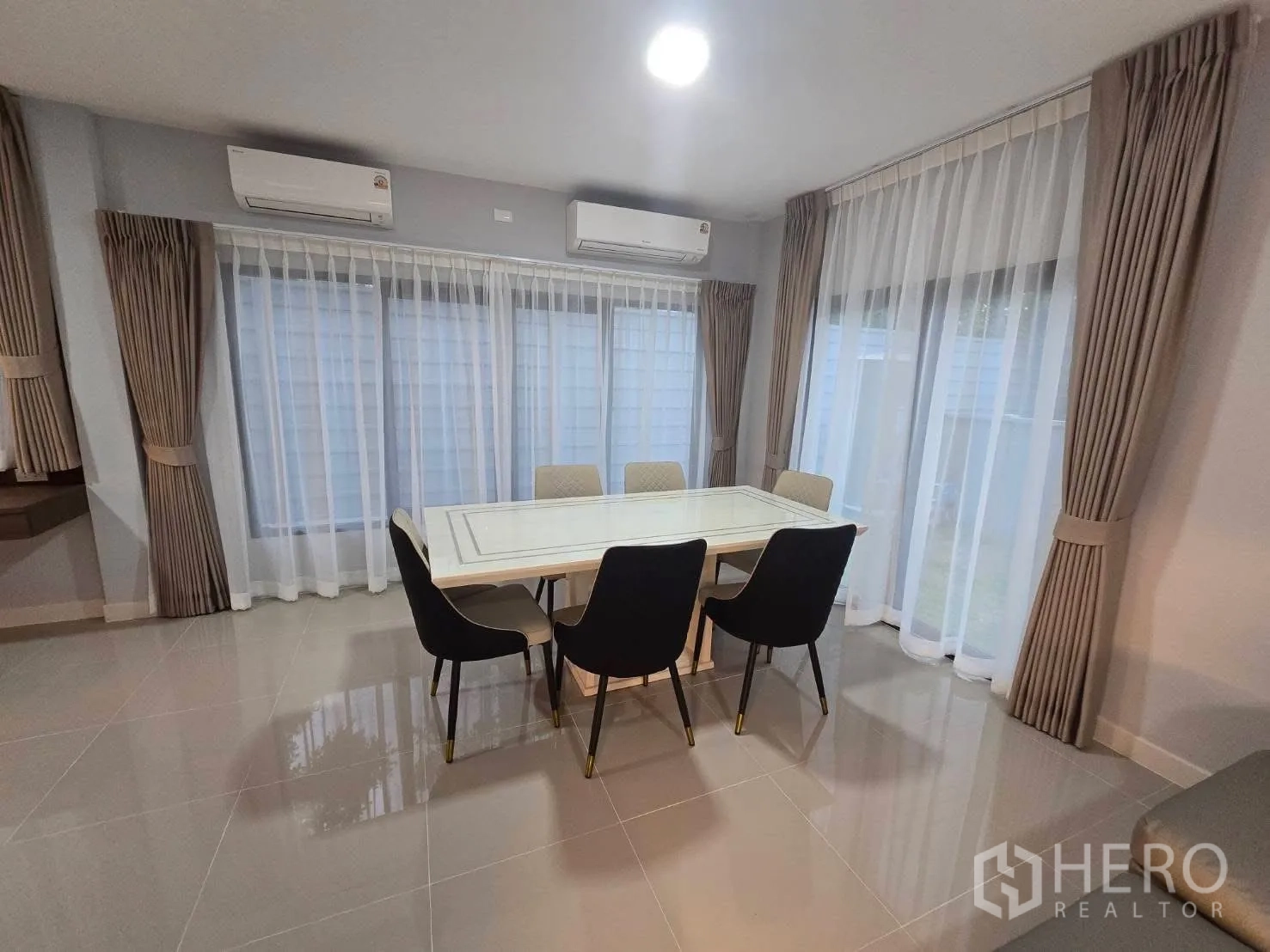 Semi-detached House for rent in Bang Phli, Samut Prakan - Dining space by wide windows with curtains and twin air conditioners.