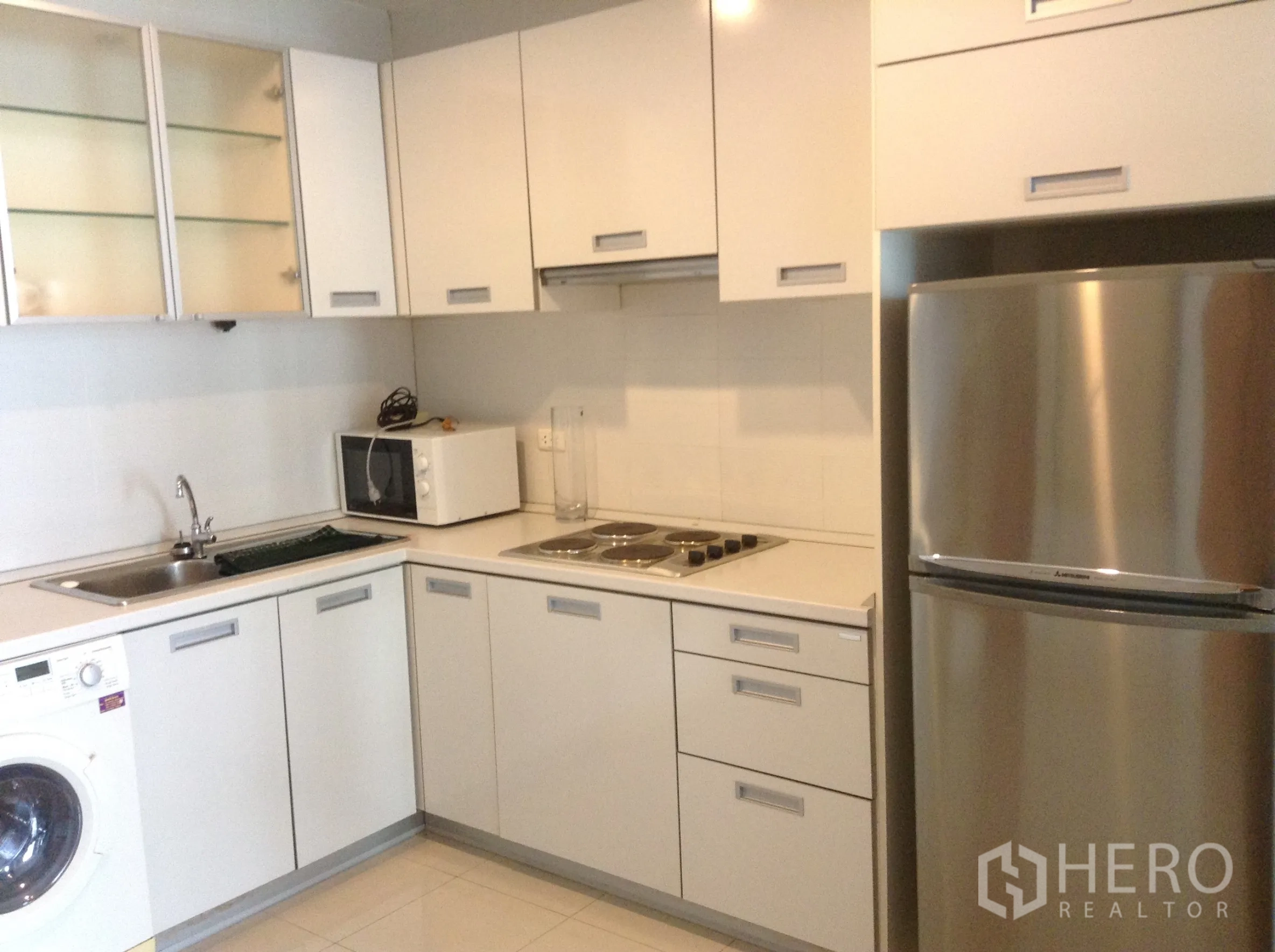 คอนโด ให้เช่าหรือขายในKhlong San, Bangkok - ครัวรูปตัวแอลโทนขาว พร้อมเตาไฟฟ้า ไมโครเวฟ เครื่องซักผ้า และตู้เย็นสแตนเลส