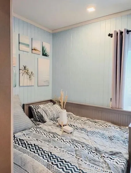 公寓 出租或出售 - 卧室以淡蓝色木质墙面与窗光营造温馨氛围，床品有图案装饰。