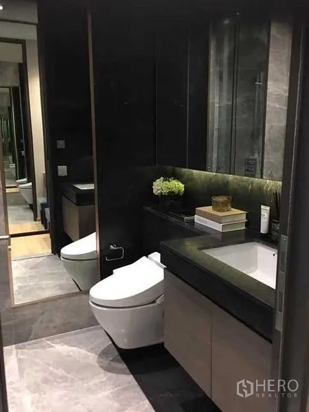 Condominium for rent - Modern bathroom with dark vanity, mirror cabinets and toilet.