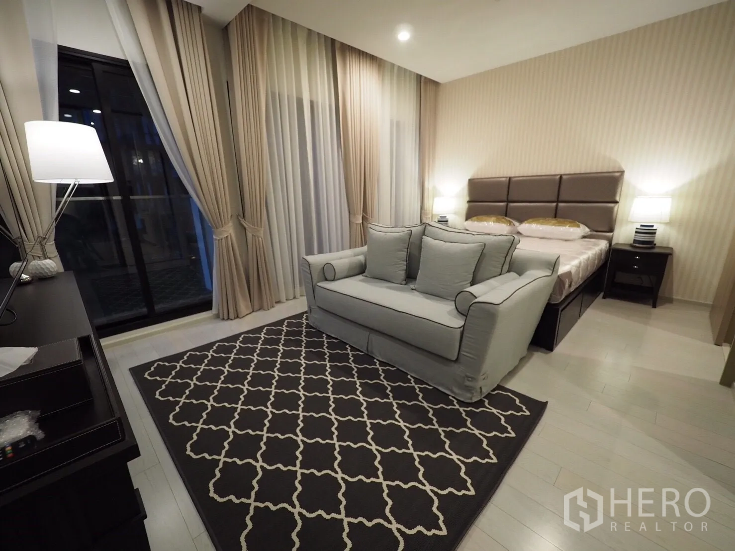 คอนโด ให้เช่าหรือขายในPathum Wan, Bangkok - ห้องนอนสวีทพร้อมเตียงบุผ้า โซฟาเลิฟซีท แสงไฟนุ่มนวล และผ้าม่านสูงจรดเพดาน