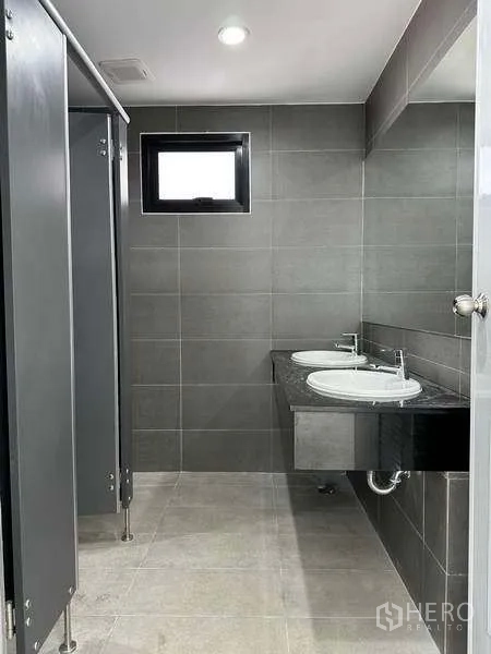 工厂 出租在Bang Phli, Samut Prakan - 现代员工卫生间，灰色瓷砖、隔间与双洗手盆。
