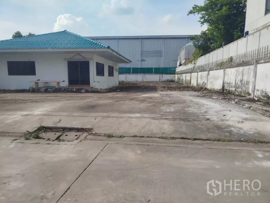 Detached House for rent or sale in Bang Na, Bangkok - Single-storey detached house with teal roof in Bang Na, set behind a perimeter wall with a wide concrete yard.