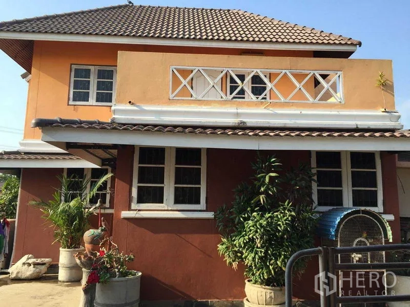 Detached House for rent or sale in Bang Bua Thong, Nonthaburi - Side elevation showing upper terrace with white railing and multiple windows under a tiled roof.