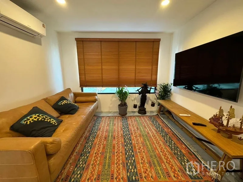 公寓 出租或出售 - 舒适客厅，皮沙发、大屏电视、百叶窗与彩色地毯。