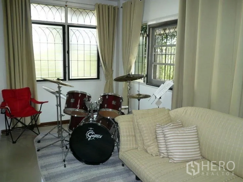Detached House for rent in Bang Kapi, Bangkok - Cozy music room with drum kit beside curtained windows and a sofa.
