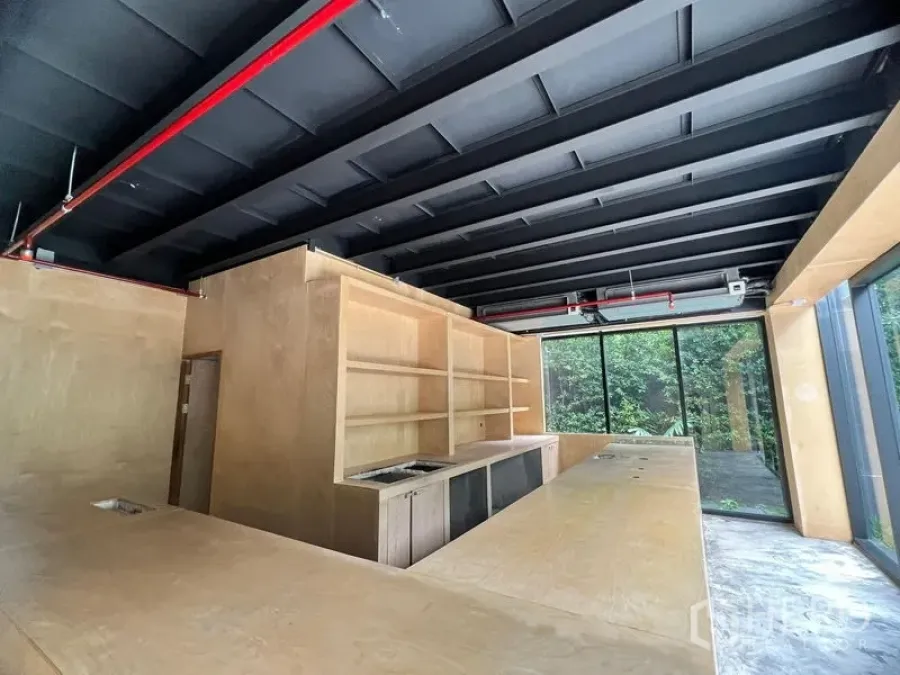 พื้นที่ขายปลีก ให้เช่าในWatthana, Bangkok - ภายในพื้นที่ค้าปลีกพร้อมเคาน์เตอร์ไม้ เพดานเปิดโล่งสีดำ และกระจกเต็มบานมองเห็นต้นไม้ ในเขตวัฒนา กรุงเทพฯ