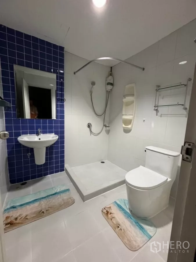 Townhouse for rent in Bang Kho Laem, Bangkok - Modern bathroom with blue tile wall, raised shower area, water heater and toilet.