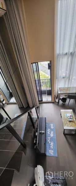 Condominium for rent - View from stairs over the double-height living room with tall curtains and balcony.