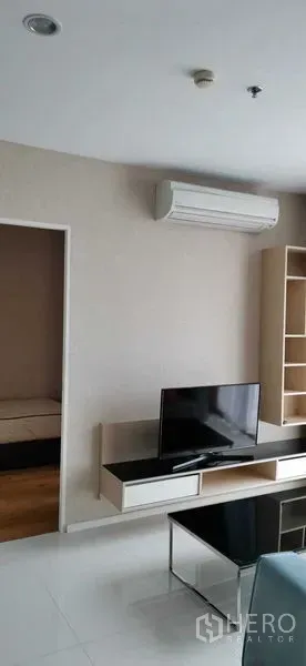 公寓 出租在Watthana, Bangkok - 客厅带壁挂电视柜、开放式书架与空调。