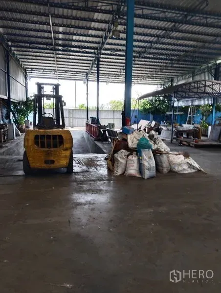 Warehouse for sale in Sai Noi, Nonthaburi - Covered loading bay with a forklift and stacked materials inside an open-sided warehouse.