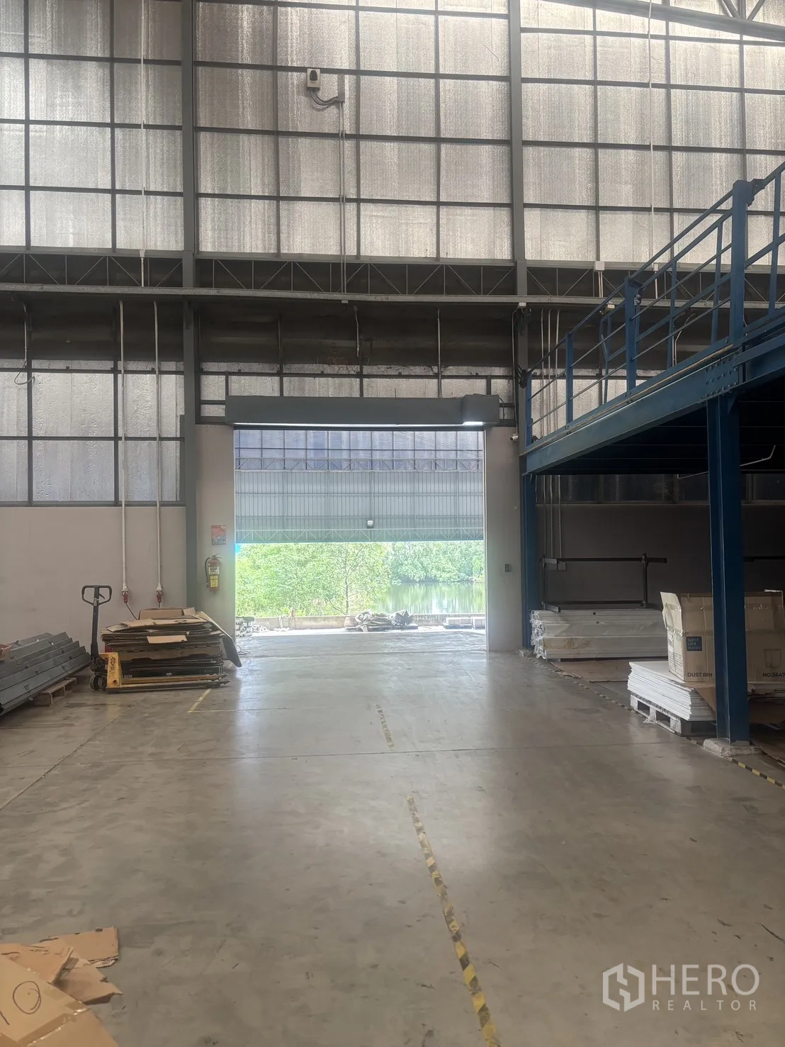 Warehouse for rent in Mueang Samut Sakhon, Samut Sakhon - Loading area with a large roller shutter opening to the outside, mezzanine platform and pallets.