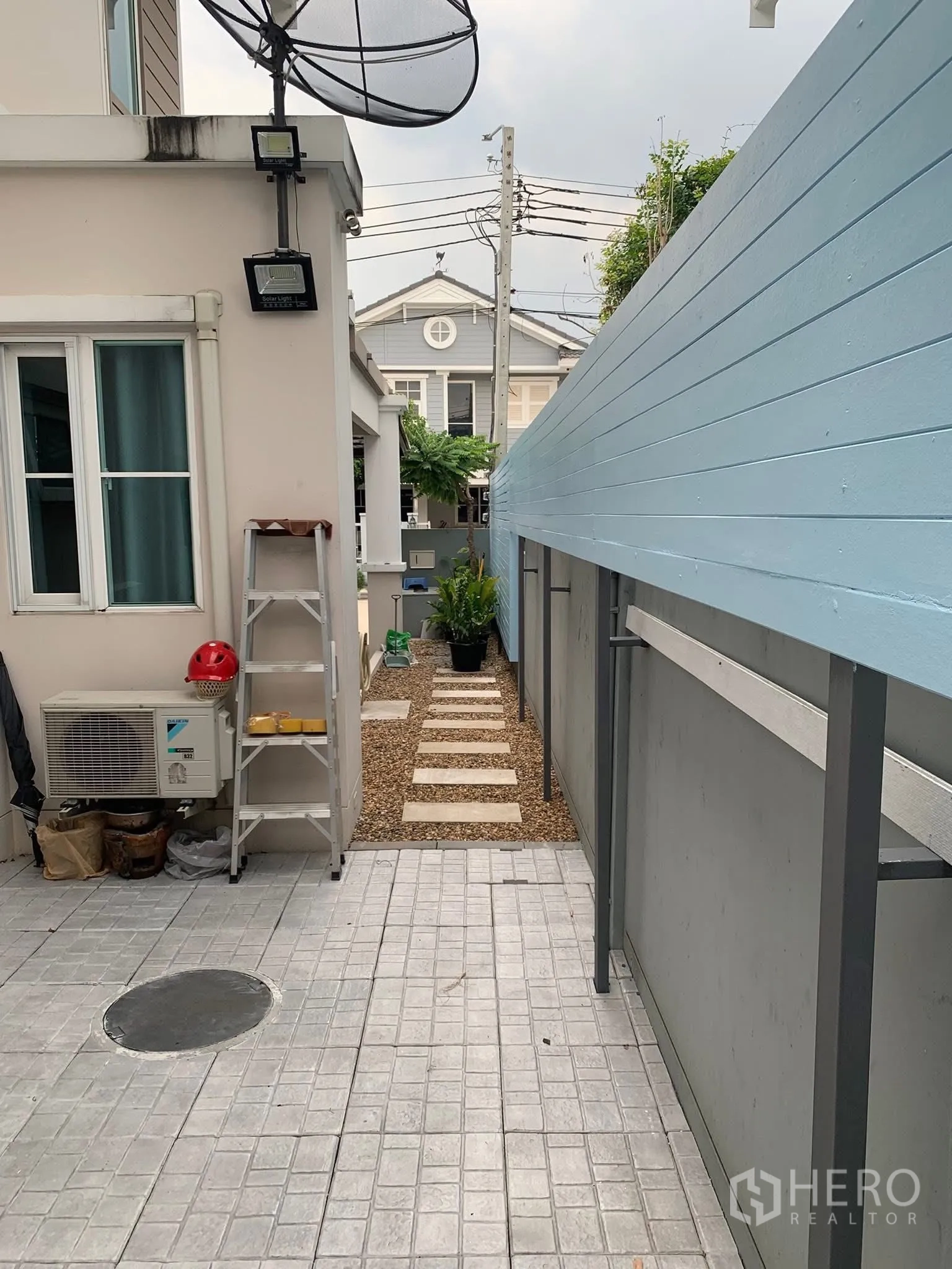 Townhouse for rent or sale in Sai Mai, Bangkok - Side yard with utility area and stepping-stone path along the fence.