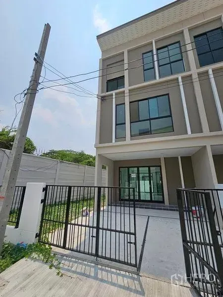 Townhouse for rent in Bang Kapi, Bangkok - Three-storey modern townhouse facade with black gate and driveway in Hua Mak, Bang Kapi.