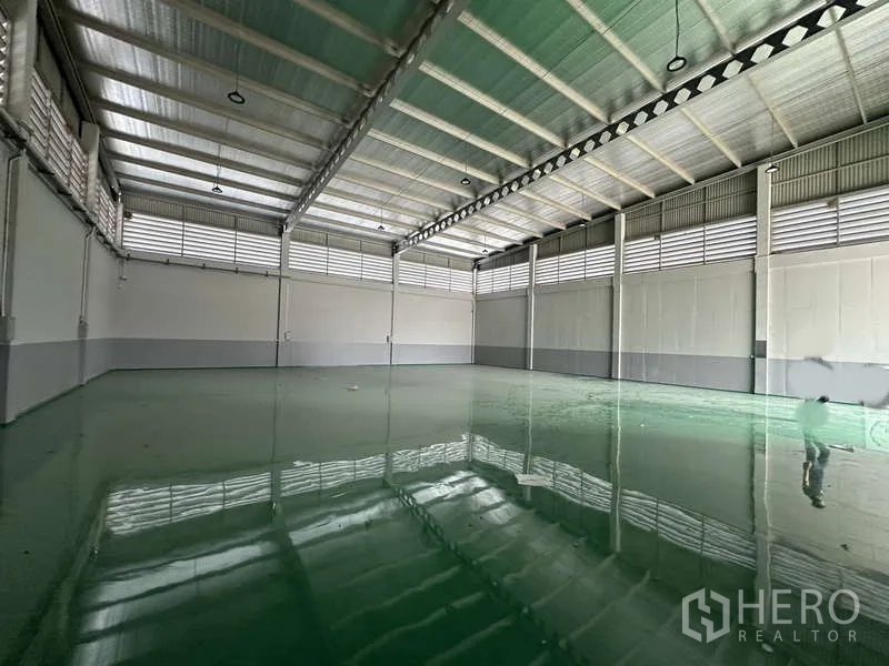 Factory for rent in Lam Luk Ka, Pathum Thani - Wide-angle view of clear-span warehouse with skylights and polished epoxy flooring.