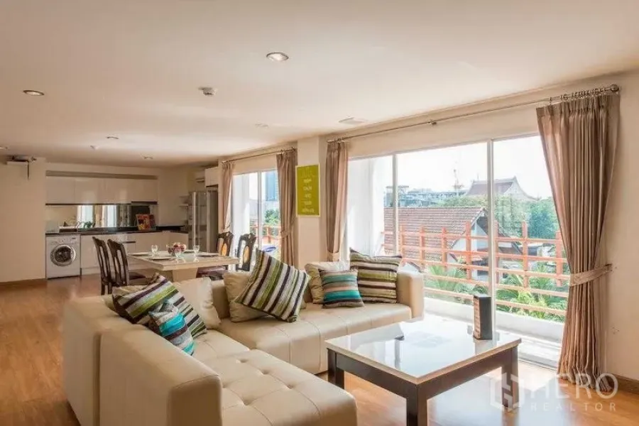 คอนโด ให้เช่าในKhlong Toei, Bangkok - ห้องนั่งเล่นพร้อมโซฟาเข้ามุม โต๊ะกลาง และหน้าต่างบานใหญ่เห็นวิวหลังคาอาคารต่ำ