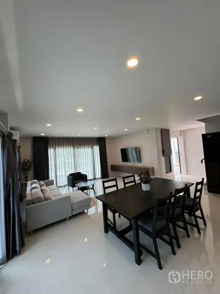 Detached House for rent in Don Mueang, Bangkok - Bright open-plan living and dining room with sofa set, six-seat table, large windows, curtains and glossy tile floors.