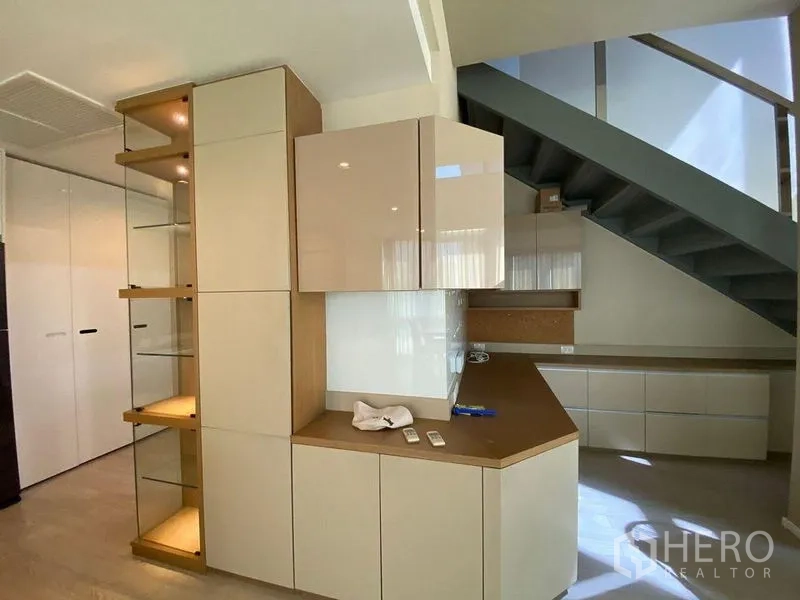 คอนโด ขายในWatthana, Bangkok - พื้นที่นั่งเล่นคอนโดสมัยใหม่ พร้อมตู้บิลท์อิน ชั้นโชว์ และบันได พื้นไม้โทนอ่อน