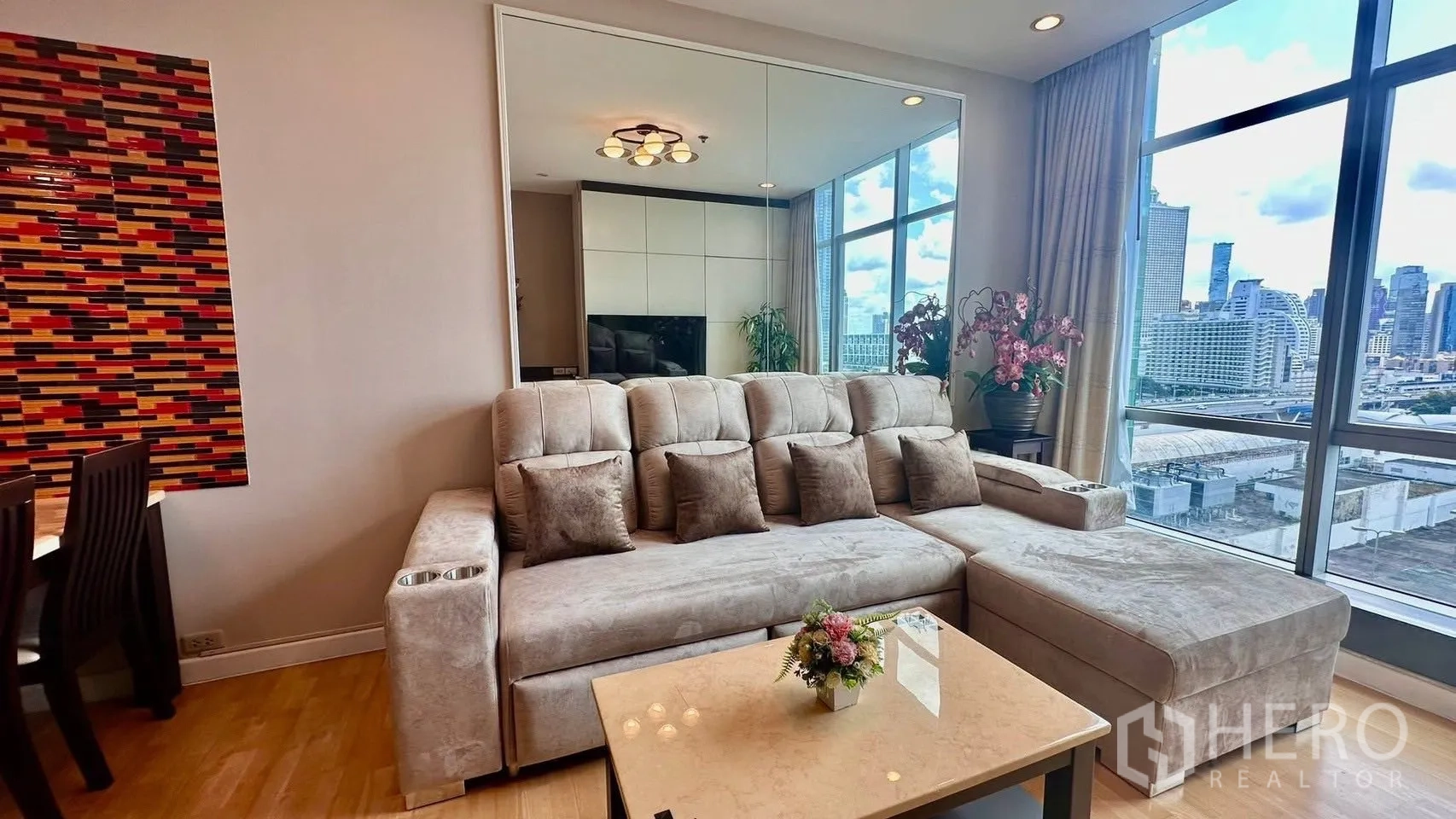公寓 for rent in Khlong San, Bangkok - 采光充足的客厅，L形沙发、茶几、餐区与落地窗，眺望城市景观。