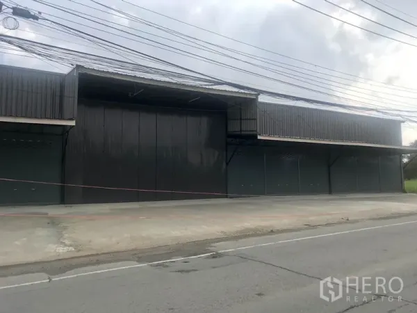 Warehouse for rent in Pathum Thani - Street-facing warehouse exterior with multiple roller shutters and wide concrete apron.