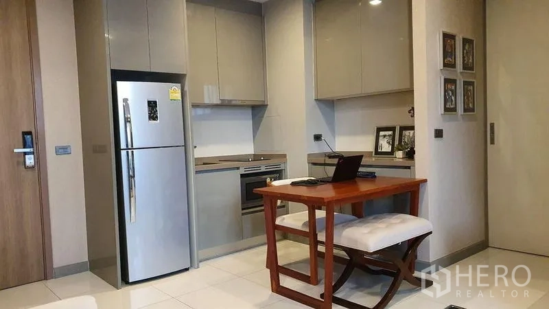 公寓 出售在Bang Rak, Bangkok - 灰色橱柜与嵌入式烤箱的小厨房，配餐桌和双门冰箱。