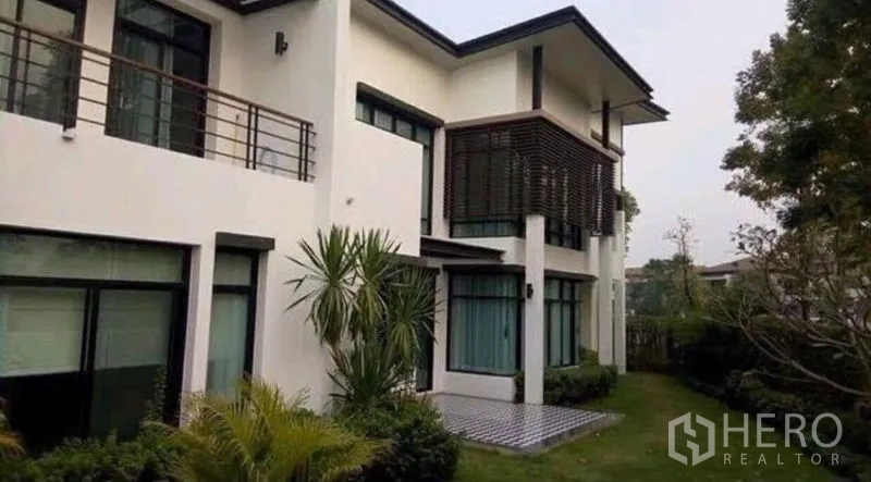 Detached House for sale in Saphan Sung, Bangkok - Rear facade of a modern detached house with balconies, sunshades and landscaped garden.