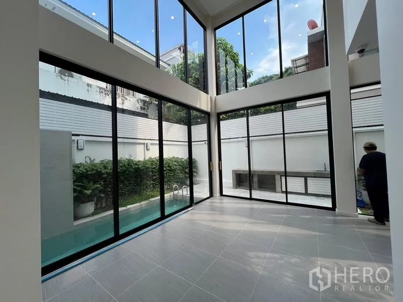 สำนักงานที่บ้าน ขายในPhra Khanong, Bangkok - พื้นที่นั่งเล่นเพดานสูงสองชั้น กระจกเต็มผนัง เปิดออกสู่คอร์ตยาร์ดและสระว่ายน้ำส่วนตัว.