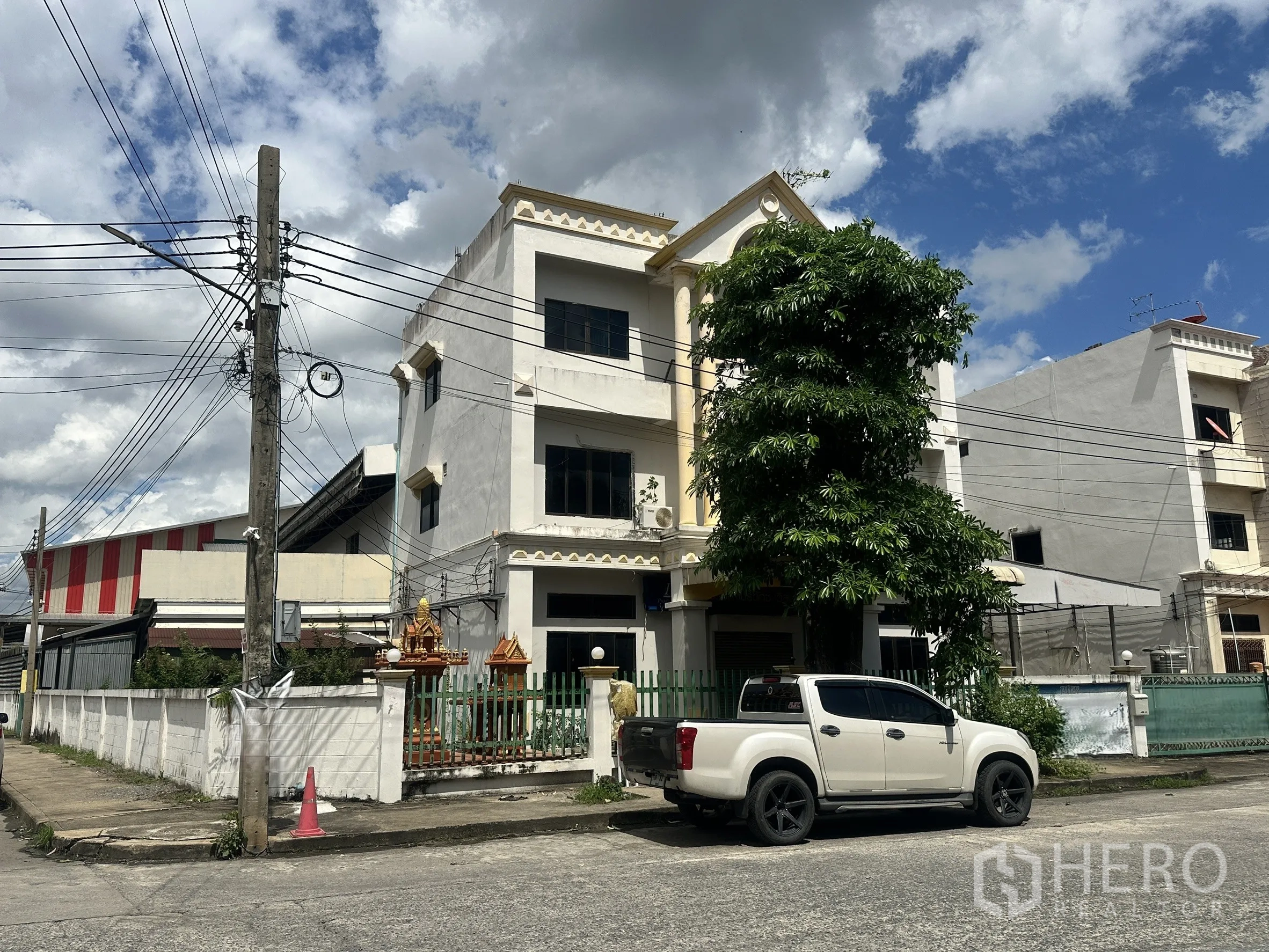 Factory for sale in Bang Bua Thong, Nonthaburi - Street view of the three-story building with gated frontage and a pickup truck.
