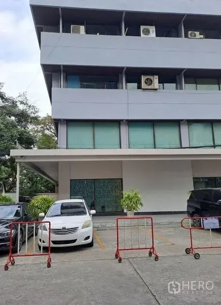 Office Space for rent in Khlong Toei, Bangkok - Low-rise office building exterior in Bangkok with parking bays and visible air-conditioning units.